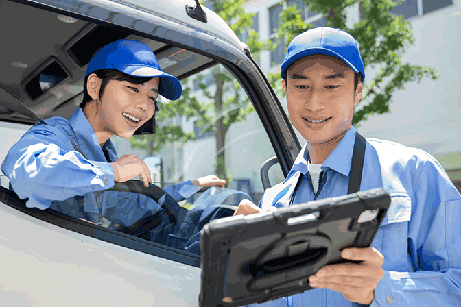 タブレットで配車情報や配送予定を共有する物流スタッフと女性ドライバーの連携シーン